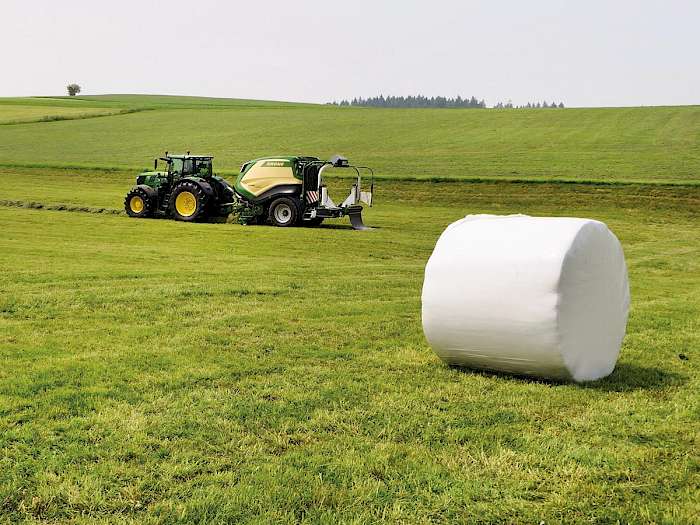 Rundballen auf Feld Maschine im Hintergrund