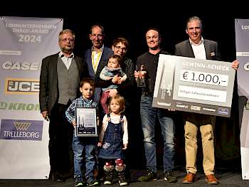Zu den vier Preisträgern des LOHNUNTERNEHMEN Image-Award 2024 gehört auch die Lohnunternehmer-Familie Villiger aus Alikon in der Schweiz. Margrit (Mitte mit den Kindern) und Marcel Villiger (2.v.r.) freuten sich über Preis und Glückwünsche von Marc Zimmermann (r., Vertriebsleiter Agrar JCB Deutschland). (Foto: Lützen)